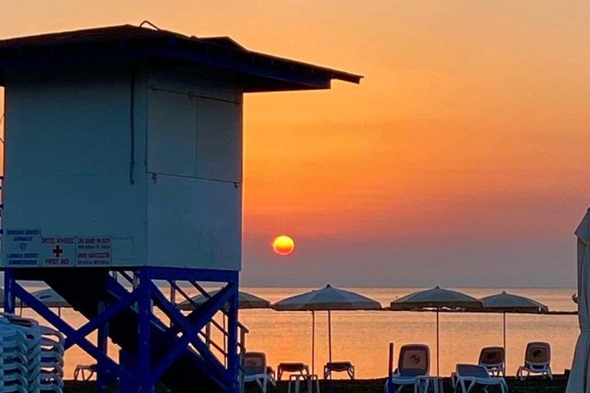 Una torre de salvavidas, sombrillas de playa y sillas de descanso al atardecer. 5
