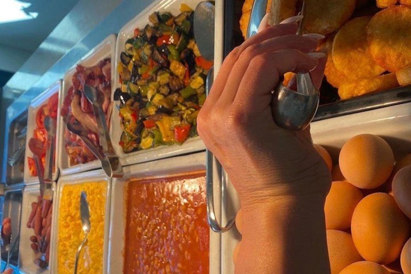 Una mano elige comida de un bufé con varios platos a la vista. 3