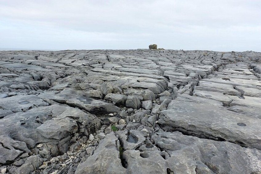 A rocky terrain with large boulders and a distant structure. 3