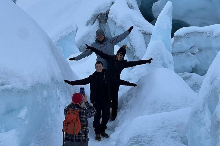 Un groupe de personnes se tient sur une formation de glace recouverte de neige, les bras tendus. 2