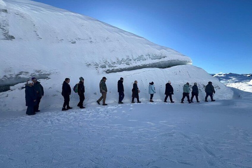 Un groupe de personnes marchant sur une montagne enneigée. 4