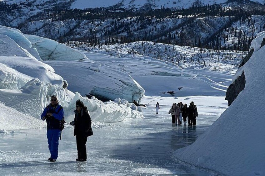 A group of people standing on a frozen river with icebergs in the background. 2