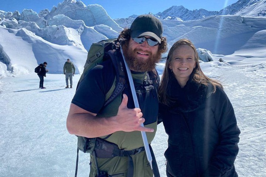 A person with a backpack and another person standing in a snowy mountainous area. 2