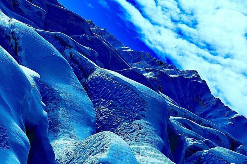 A rugged mountain landscape with snow-covered peaks and a clear blue sky. 4
