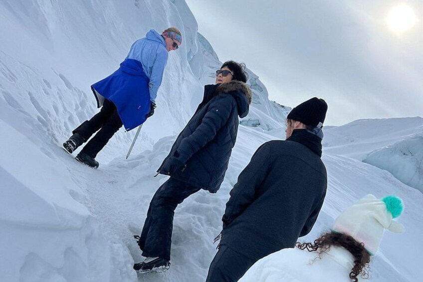 Trois personnes se trouvent dans une région montagneuse enneigée, et l’une d’entre elles tient un bâton de marche. 5
