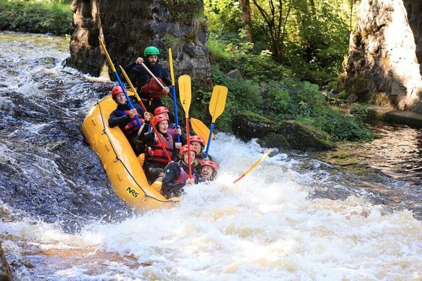 A group of people in a yellow raft navigating a river with rapids. 1