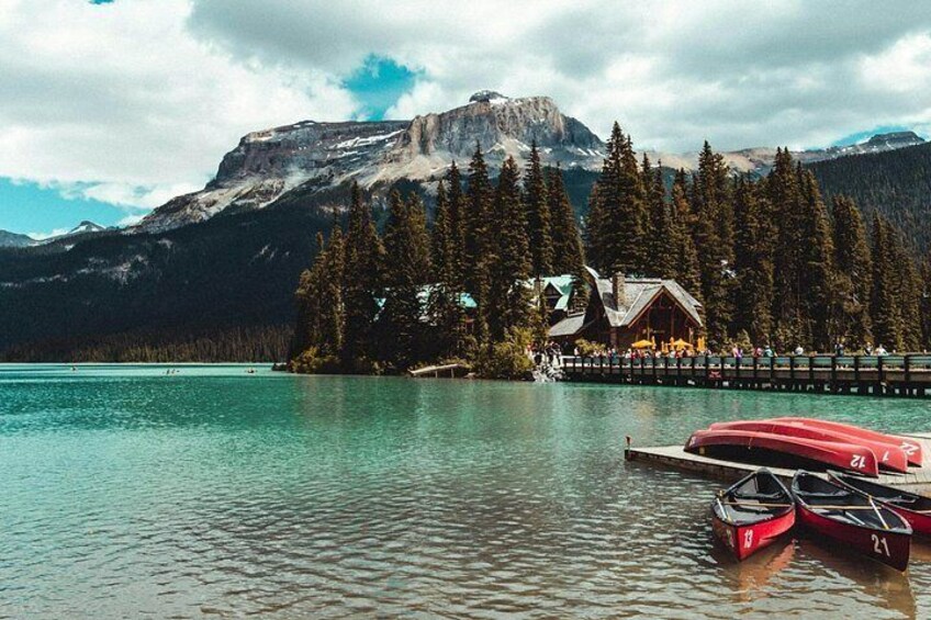 A lake with a cabin, red boats, and a mountain in the background. 2