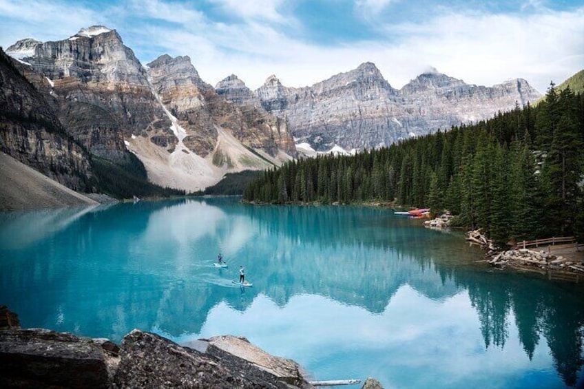 A turquoise lake surrounded by mountains, with two paddleboards in the water. 5