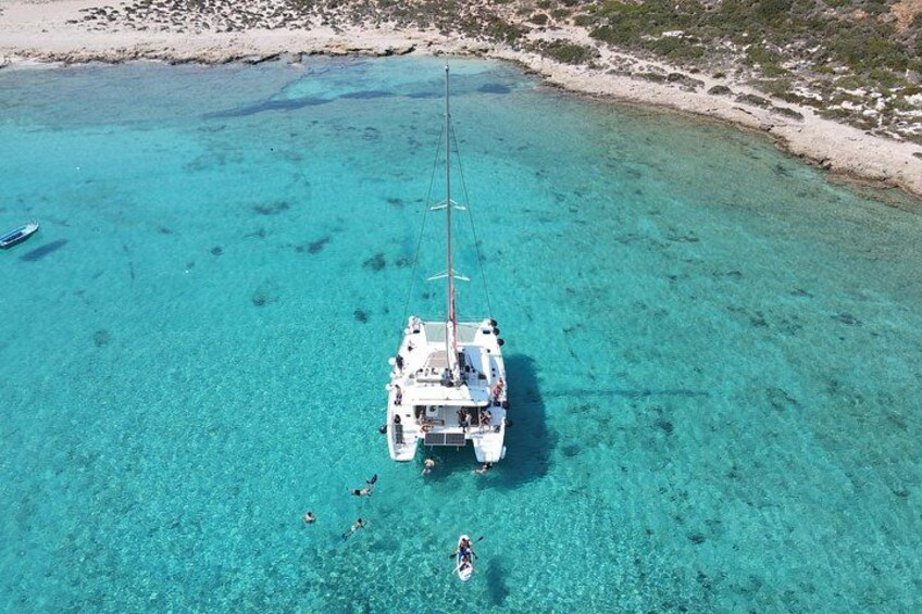 A white boat anchored in clear turquoise waters with a sandy beach and sparse vegetation in the background. 4