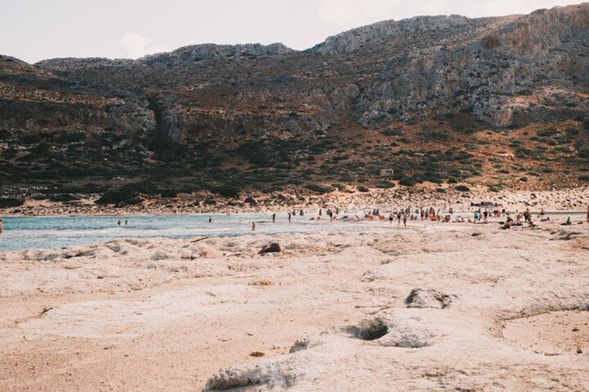 A rocky beach with people swimming and walking. 3
