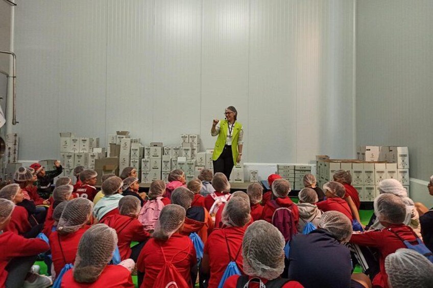 A person speaking to a group of people in a room with boxes in the background. 4