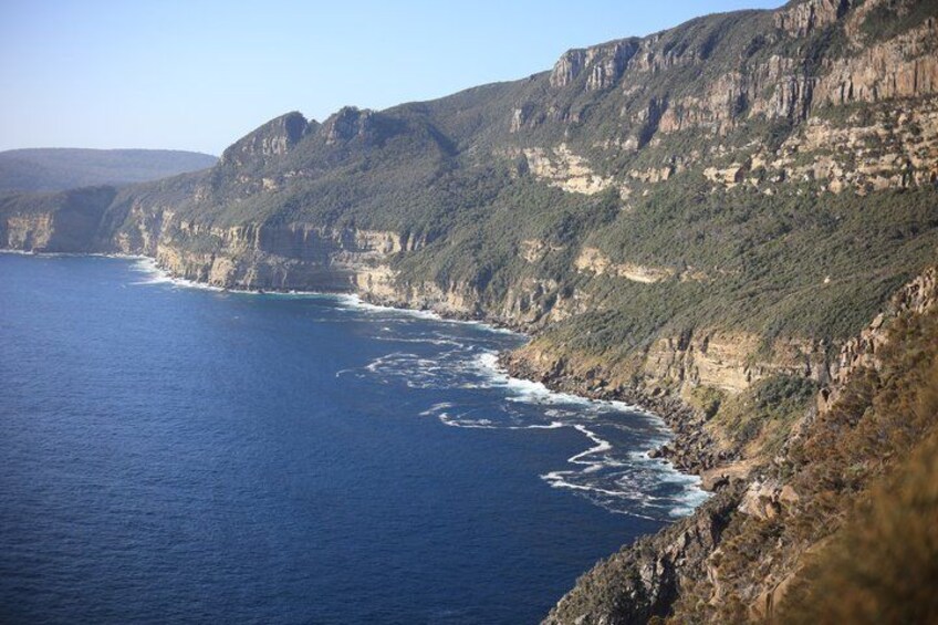 Un acantilado costero con mar azul profundo y terreno rocoso. 5