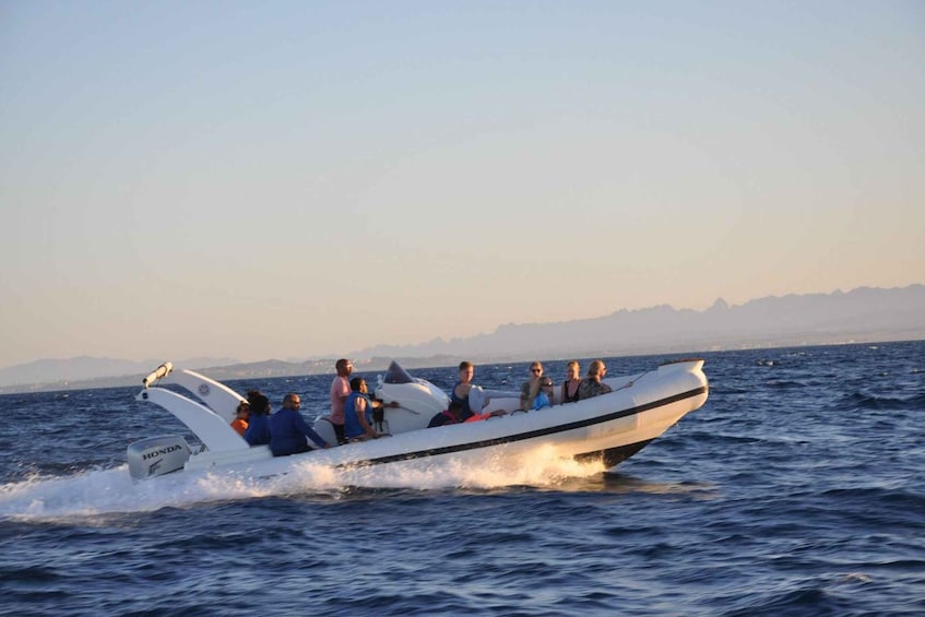 A boat with passengers on a body of water, surrounded by mountains. 2