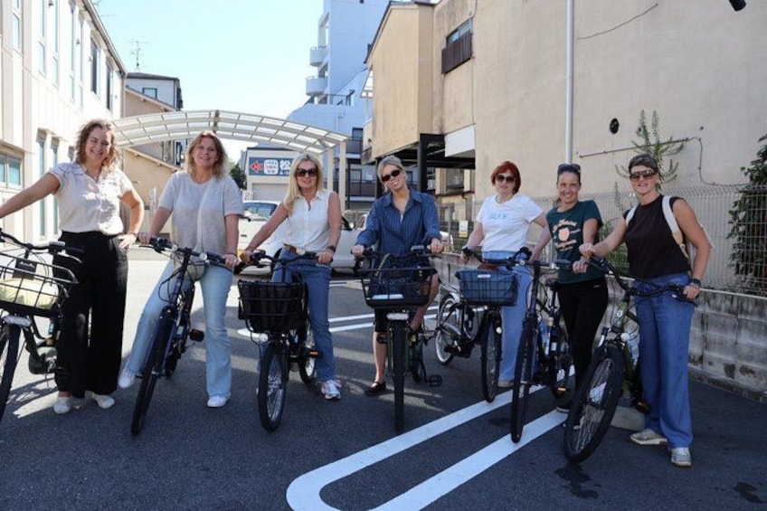 Un gruppo di persone in bicicletta in un contesto urbano, con edifici e cielo sereno. 3