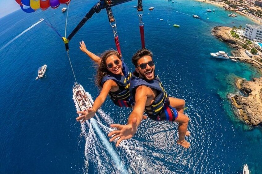 Una persona haciendo parasailing sobre una zona costera con aguas azules cristalinas y embarcaciones. 1
