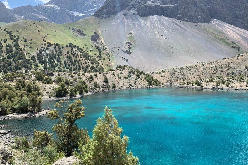 A turquoise lake surrounded by mountains and sparse vegetation. 2