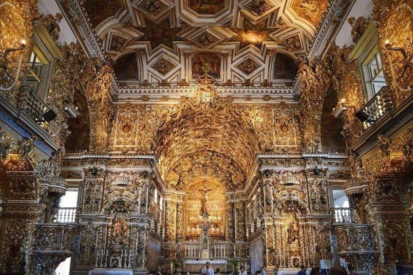 An ornate interior with intricate golden decorations, a large central altar, and a detailed ceiling. 3