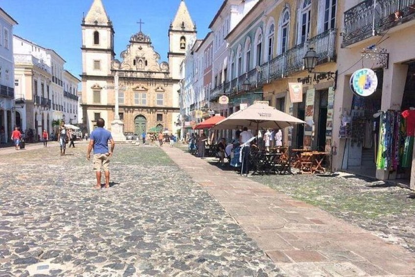 A cobblestone street with a historic church, outdoor cafes, and pedestrians. 2