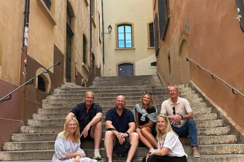 A group of people sitting on stone steps in a narrow alleyway with buildings on either side. 4
