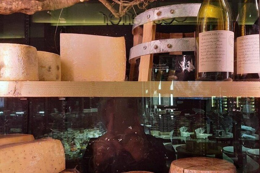 A cheese display with wheels and bottles of wine. 5