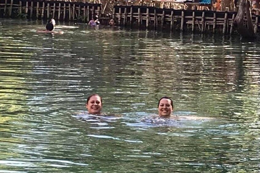 Deux personnes nagent dans une étendue d’eau, avec un quai en bois en arrière-plan. 4