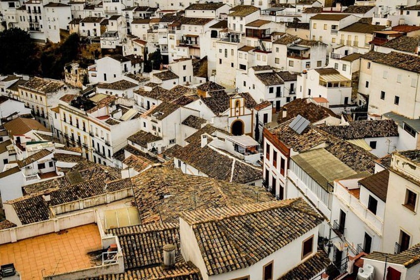 A densely packed urban area with white buildings and terracotta roofs. 1