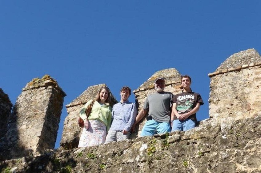 A group of people standing on a rocky outcrop with ancient ruins in the background. 5