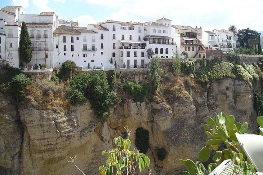 A coastal town with white buildings, cliffs, and greenery. 4