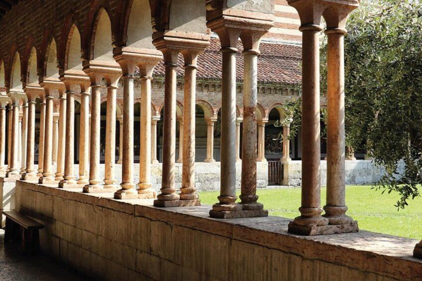 A series of stone columns in a courtyard with a building in the background. 3