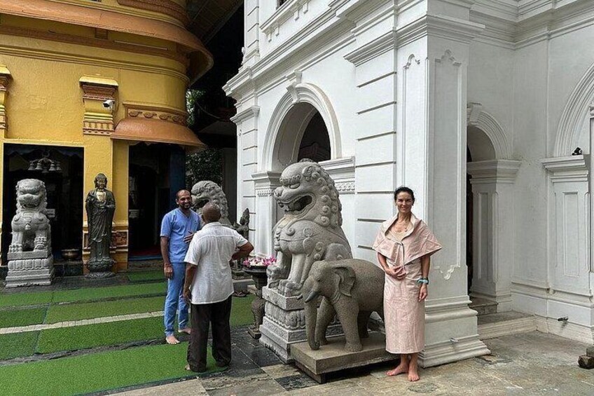 A person standing next to a stone lion statue in front of a white building with arches. 2