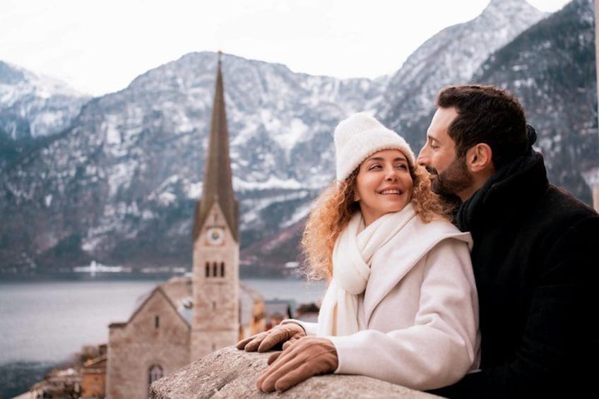 Una pareja sentada junto a un lago, con montañas al fondo. 1