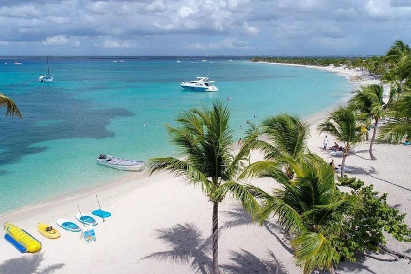 A beach with clear turquoise water, palm trees, and boats. 1