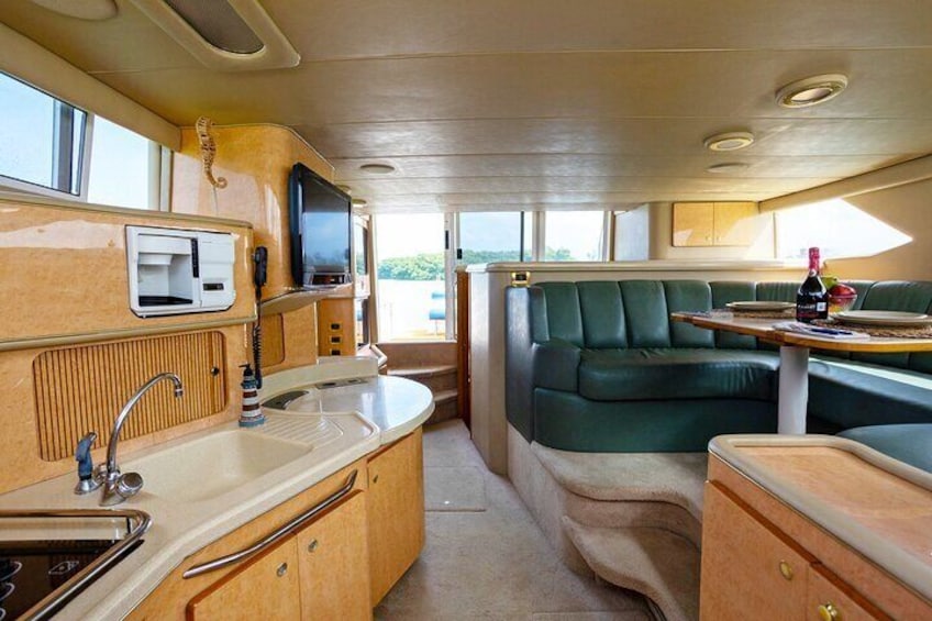 A compact kitchen with a sink, stove, and a small dining area with a table and green cushioned seating. 4