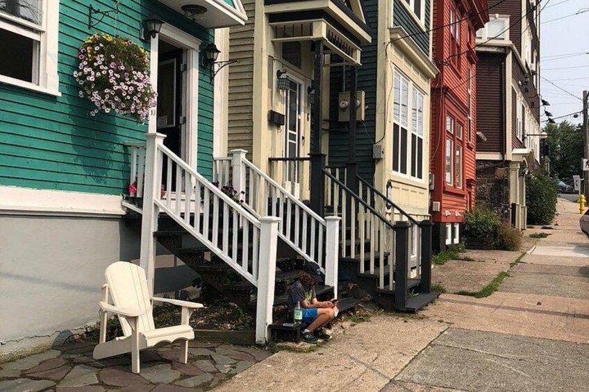 A row of colorful houses with a white chair and a person sitting on the steps. 4