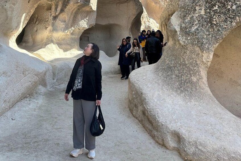 A person standing in a rock formation with a group of people in the background. 4