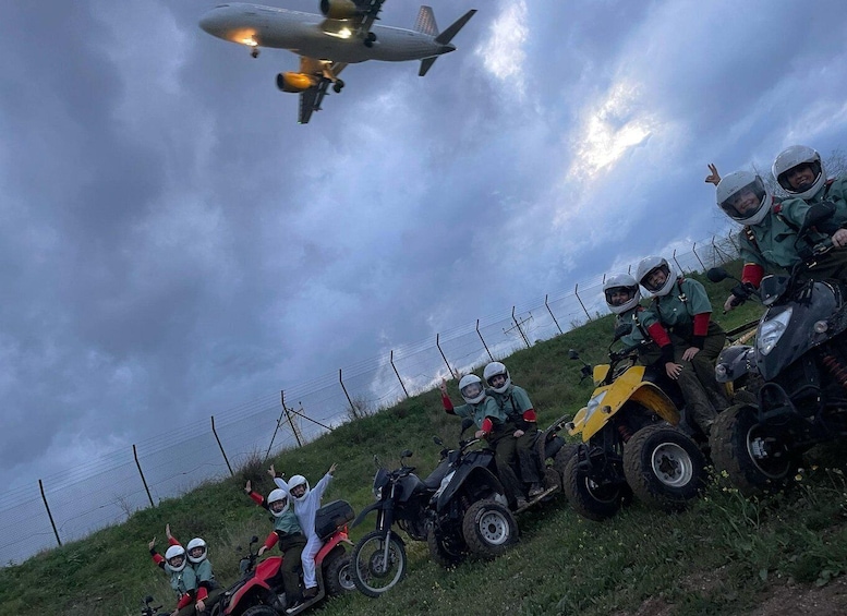 A group of people in protective gear on all-terrain vehicles (ATVs) and a military aircraft flying overhead. 2