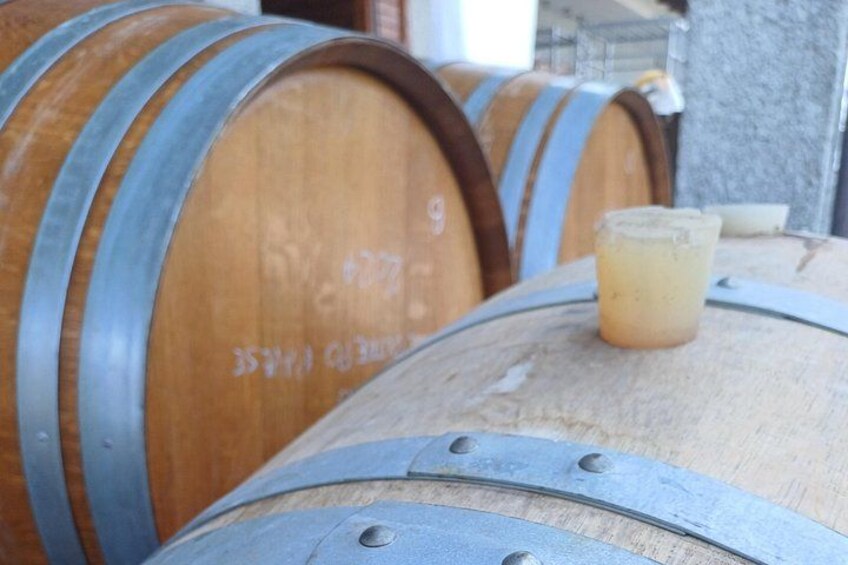 Wooden barrels with metal bands, one with a small glass container on top. 4