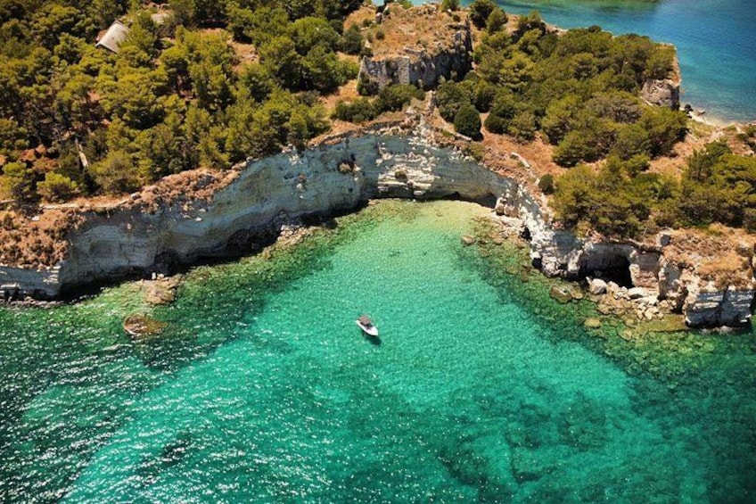 Un bateau sur une eau turquoise et limpide, entouré de falaises rocheuses et d’une végétation luxuriante. 3