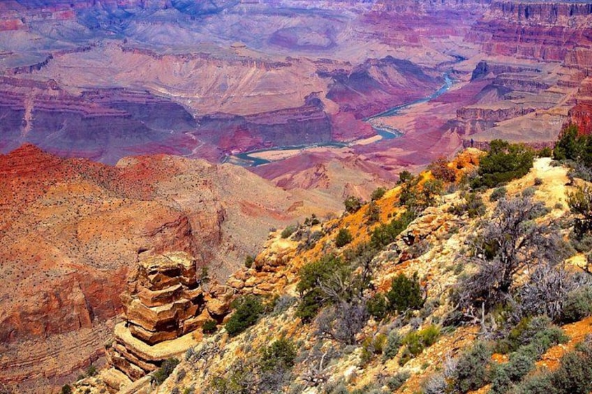 Ett canyonlandskap med lager av bergformationer och gles vegetation. 2