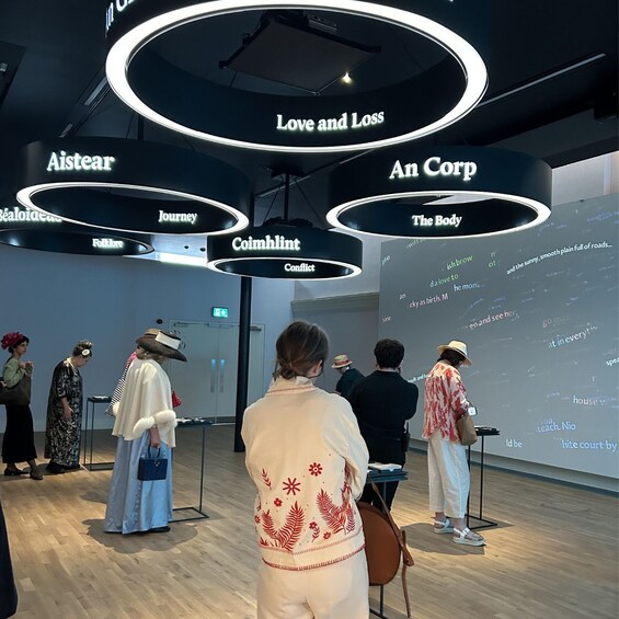 Eine Kunstgalerie mit beleuchteten Schildern mit den Aufschriften 'Love and Loss', 'An Corp', 'The Body' und 'Conflict'. 5