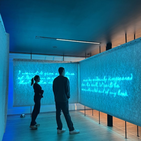 Zwei Personen betrachten eine große digitale Anzeige mit blauem Licht. 1
