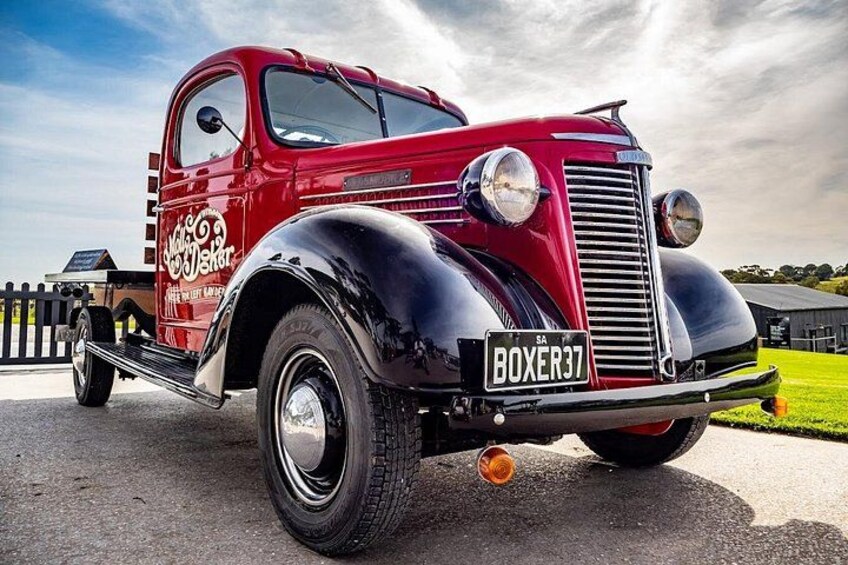 A vintage red truck with the license plate BOXER37 parked on a paved surface. 5