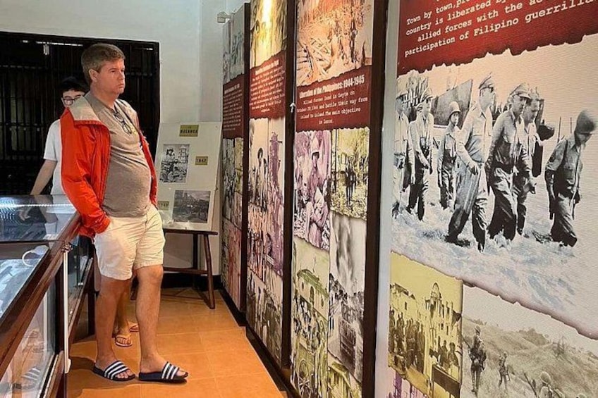 A person standing in front of a wall with historical photographs and text. 3