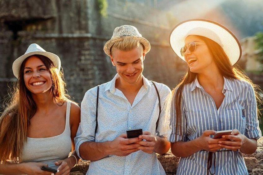 Drie mensen buiten staan, waarvan er één een smartphone vasthoudt. 2