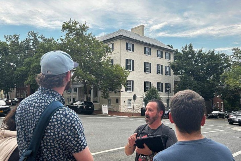 A group of people standing on a street with a building in the background. 1