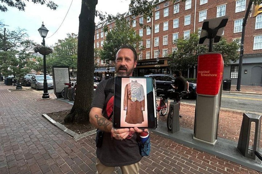 A person holding a framed picture, a tree, a lamp post, and a red sign on a brick sidewalk. 3
