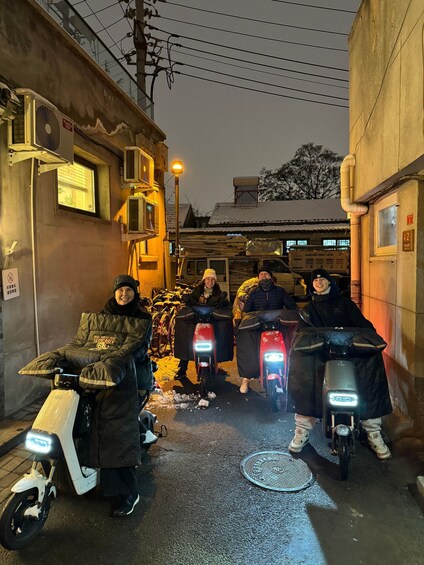 Un grupo de personas en scooters por un callejón de noche. 2