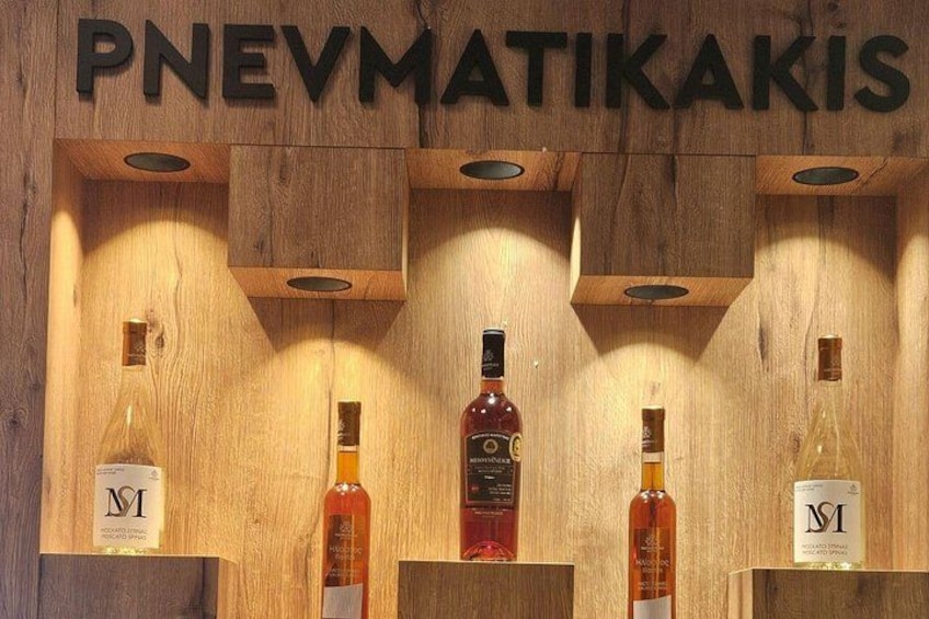 A wooden display with bottles labeled 'PNEVMATIKAKIS' and 'MI' on a wooden shelf. 3