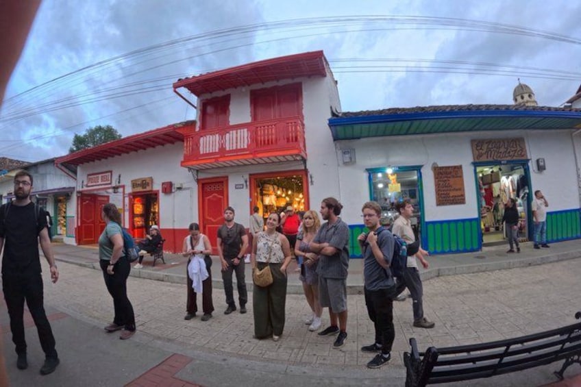 A group of people standing on a street in front of buildings with red and white facades. 5