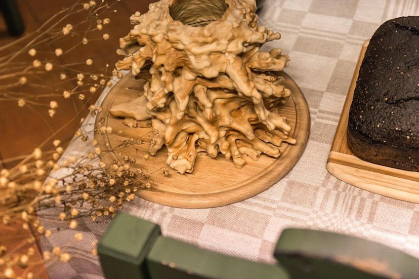 A wooden cutting board with mushrooms and a loaf of bread on a checkered tablecloth. 2